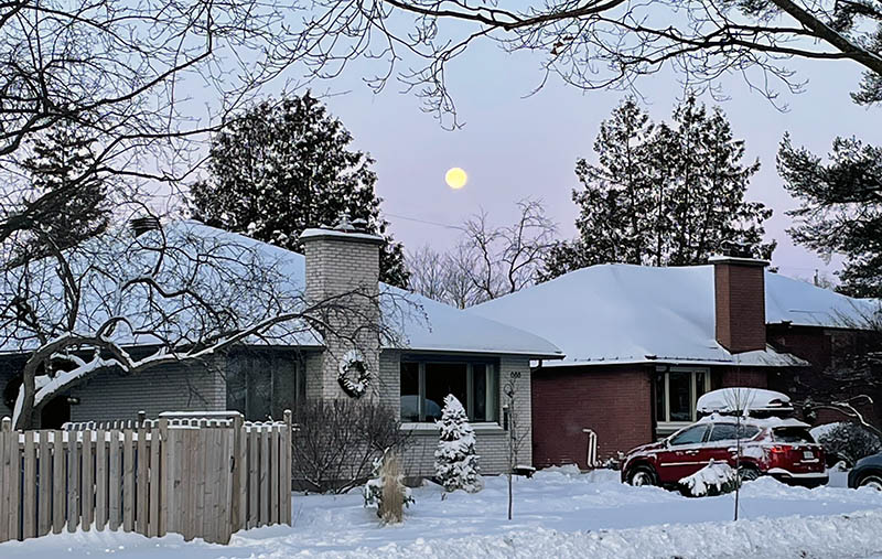 Moon over two snowy houses after a large snowfall in Ottawa